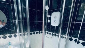 Een douchecabine met glazen wanden, een handdouche en een bedieningspaneel.