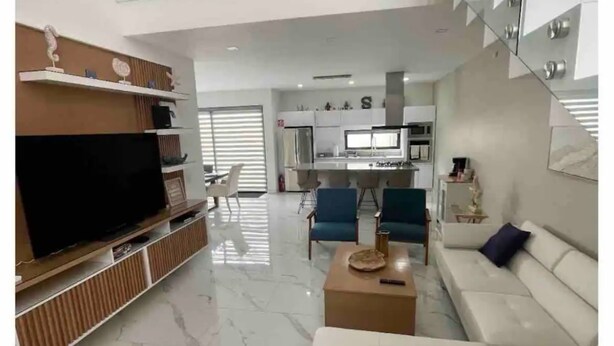 A modern living room with a flat-screen TV, a white sofa, and a coffee table. - Casa Santacruz (Ensenada)