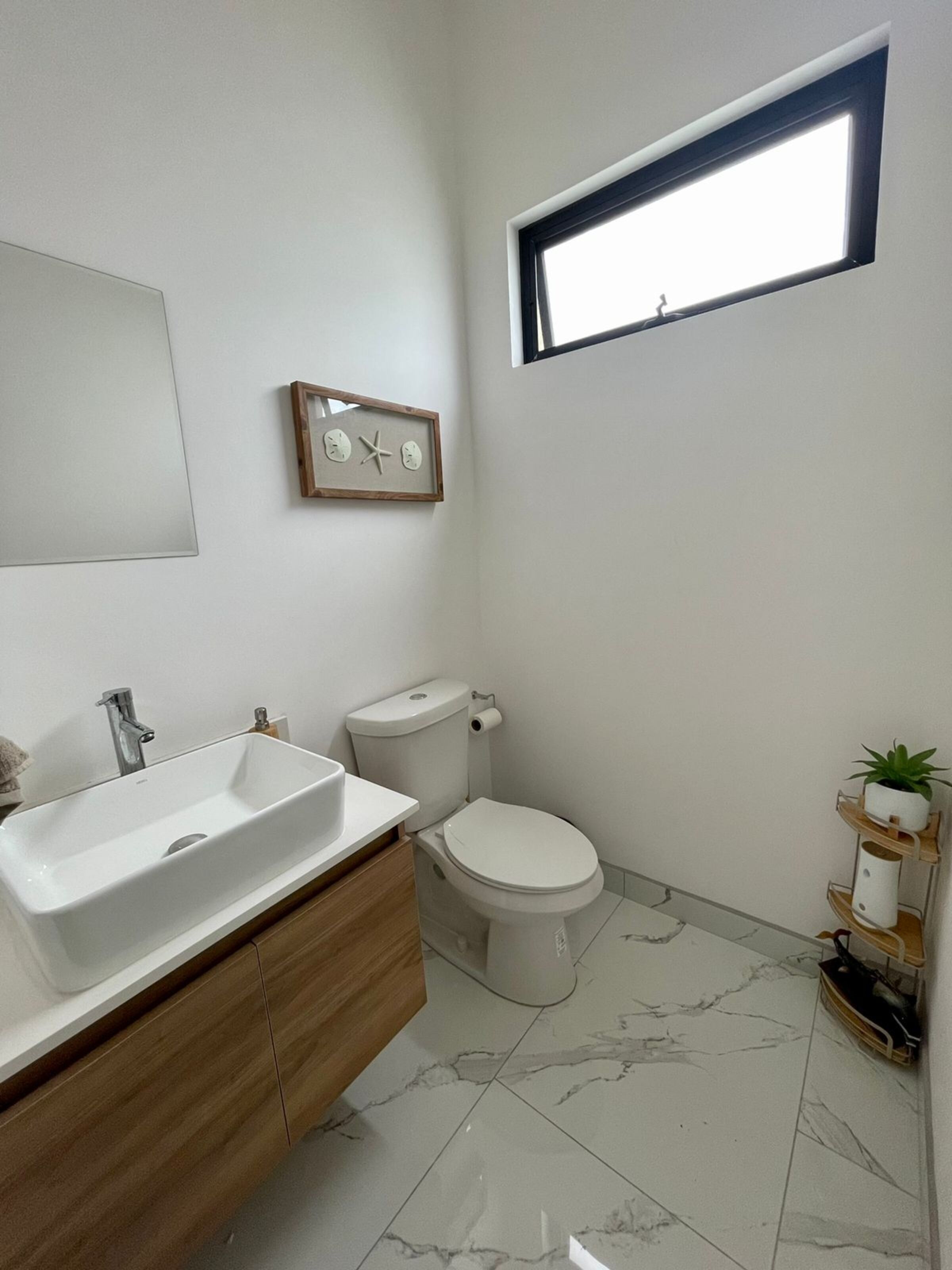 A bathroom with a large sink, toilet, and a small window.