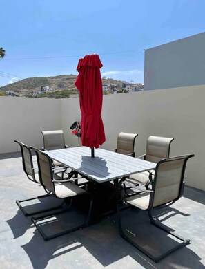 A dining table with six chairs and a red umbrella. - Casa Santacruz (Ensenada)