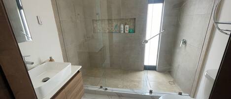 Une salle de bain moderne avec une douche à parois de verre, un lavabo blanc et des toilettes.