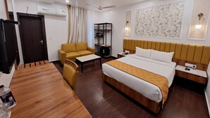 A hotel room with a bed, a sofa, a desk, a wardrobe, and a ceiling fan. - WELCOME SPA & RESORTS (Sambalpur)