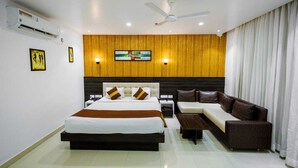 A modern hotel room with a large bed, a sofa, a coffee table, and a TV mounted on the wall. - WELCOME SPA & RESORTS (Sambalpur)