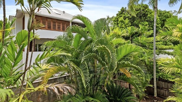 A modern house surrounded by lush tropical vegetation.