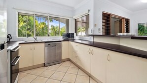 A modern kitchen with a dishwasher, microwave, and a large window with a view of palm trees.