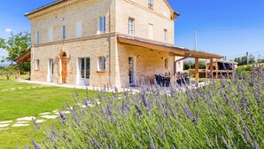 Un grand bâtiment en pierre doté d’un patio couvert et d’un jardin où l’on peut admirer la lavande.
