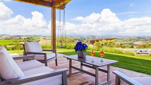 Une terrasse extérieure avec une table, des chaises et une balançoire suspendue.