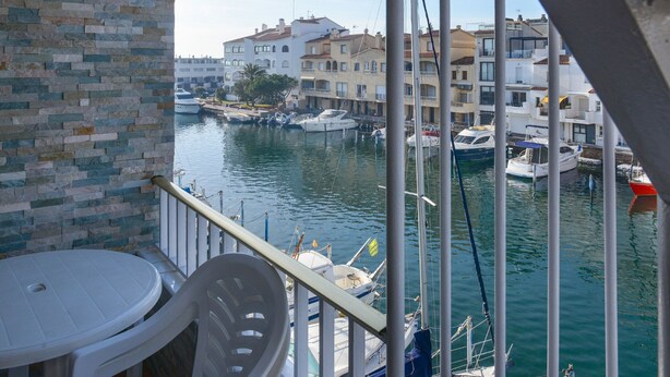 A balcony with a view of a marina, boats, and buildings in the background.
