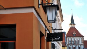 A building with a sign that reads 'FENIAN WOHNUNGEN' and a church with a red roof in the background. - Apartment 'Wohnung 'am Kütertor' - Störtebeker' with Private Terrace and Wi-Fi (Stralsund)