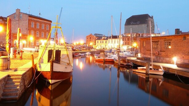 A marina with boats docked, a crane, and buildings in the background. - Apartment 'Wohnung 'am Kütertor' - Störtebeker' with Private Terrace and Wi-Fi (Stralsund)
