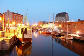 Un port de plaisance avec des bateaux amarrés, une grue et des bâtiments en arrière-plan.