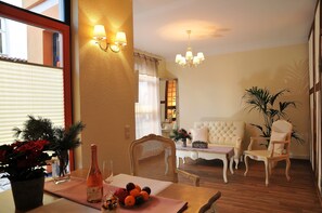 Une pièce bien éclairée, avec une table à manger dressée, un canapé et deux fauteuils.