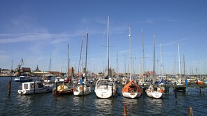A marina with multiple boats docked, a clear sky, and buildings in the background. - Apartment 'Wohnungen 'am Kütertor' - Kogge' with Balcony and Wi-Fi (Stralsund)