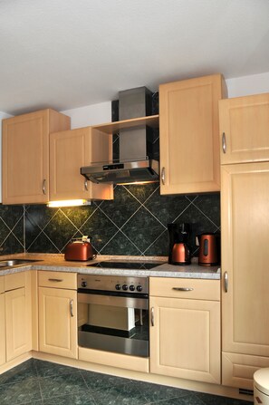 Eine Küche mit Holzausstattung, einem Edelstahlbackofen, einer Kaffeemaschine und einem Wasserkocher.