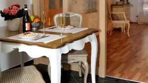 A dining area with a table set for two, a bottle of wine, and a glass of champagne. - Apartment 'Wohnungen 'am Kütertor' - Kogge' with Balcony and Wi-Fi (Stralsund)