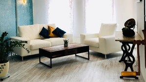 Een woonkamer met een bank, fauteuil, salontafel en een kamerplant.