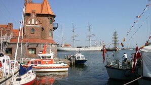 Un puerto con barcos, un edificio de ladrillo y un barco mercante al fondo.
