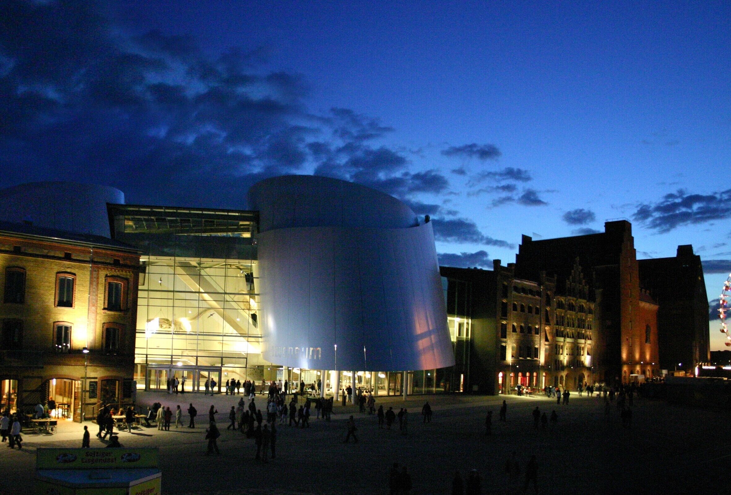 A modern building with a cylindrical structure, surrounded by traditional architecture.