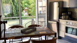 Een moderne keuken met een eethoek, grote ramen en uitzicht op groen.