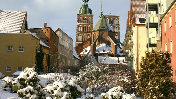 Un paysage urbain enneigé, avec une église imposante et des bâtiments environnants.