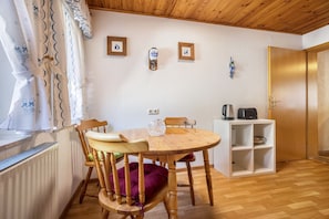 A wooden dining table with chairs, a white shelf unit, and a radiator.