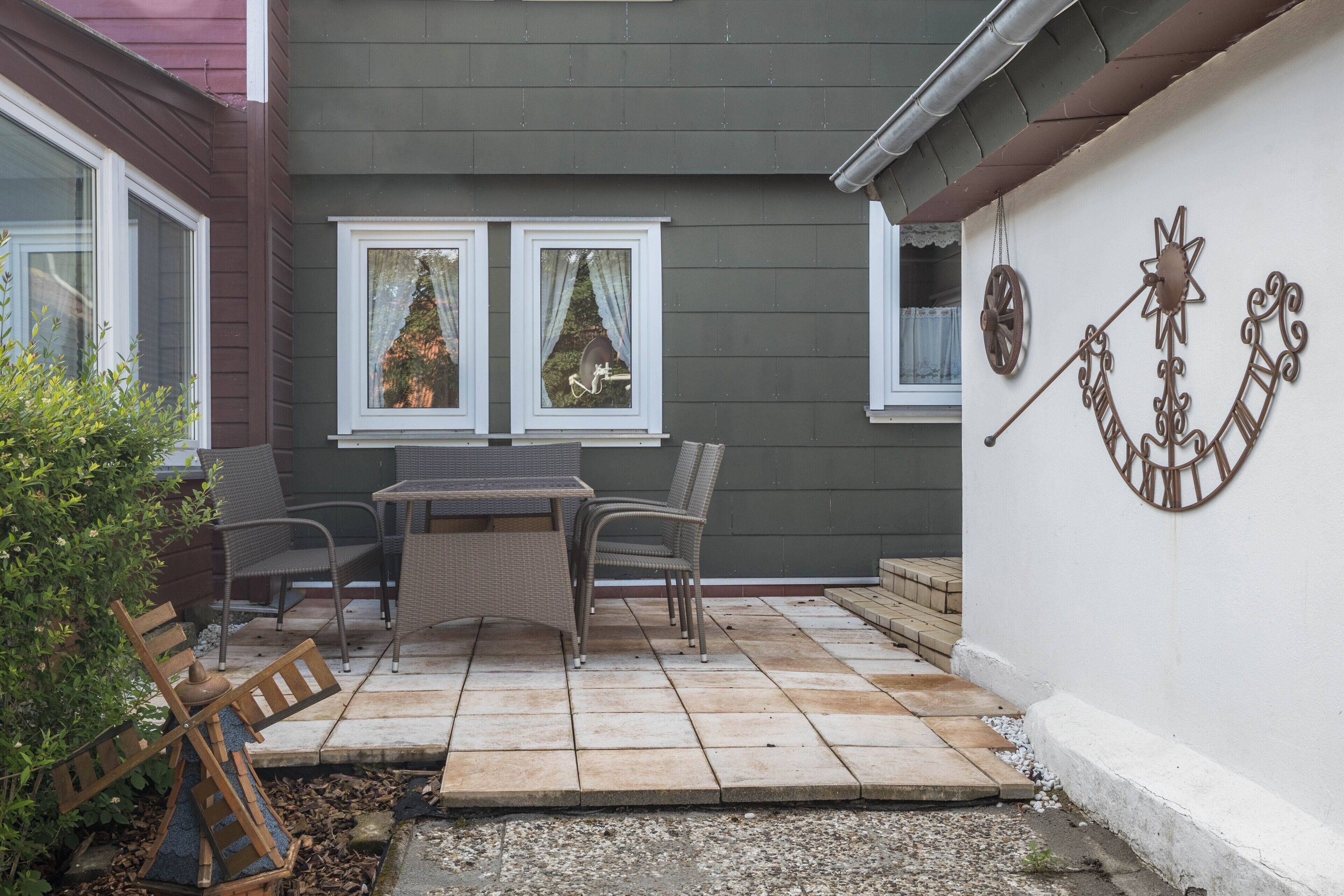 Un patio con una mesa, sillas, un adorno con forma de molino y un reloj de pared.