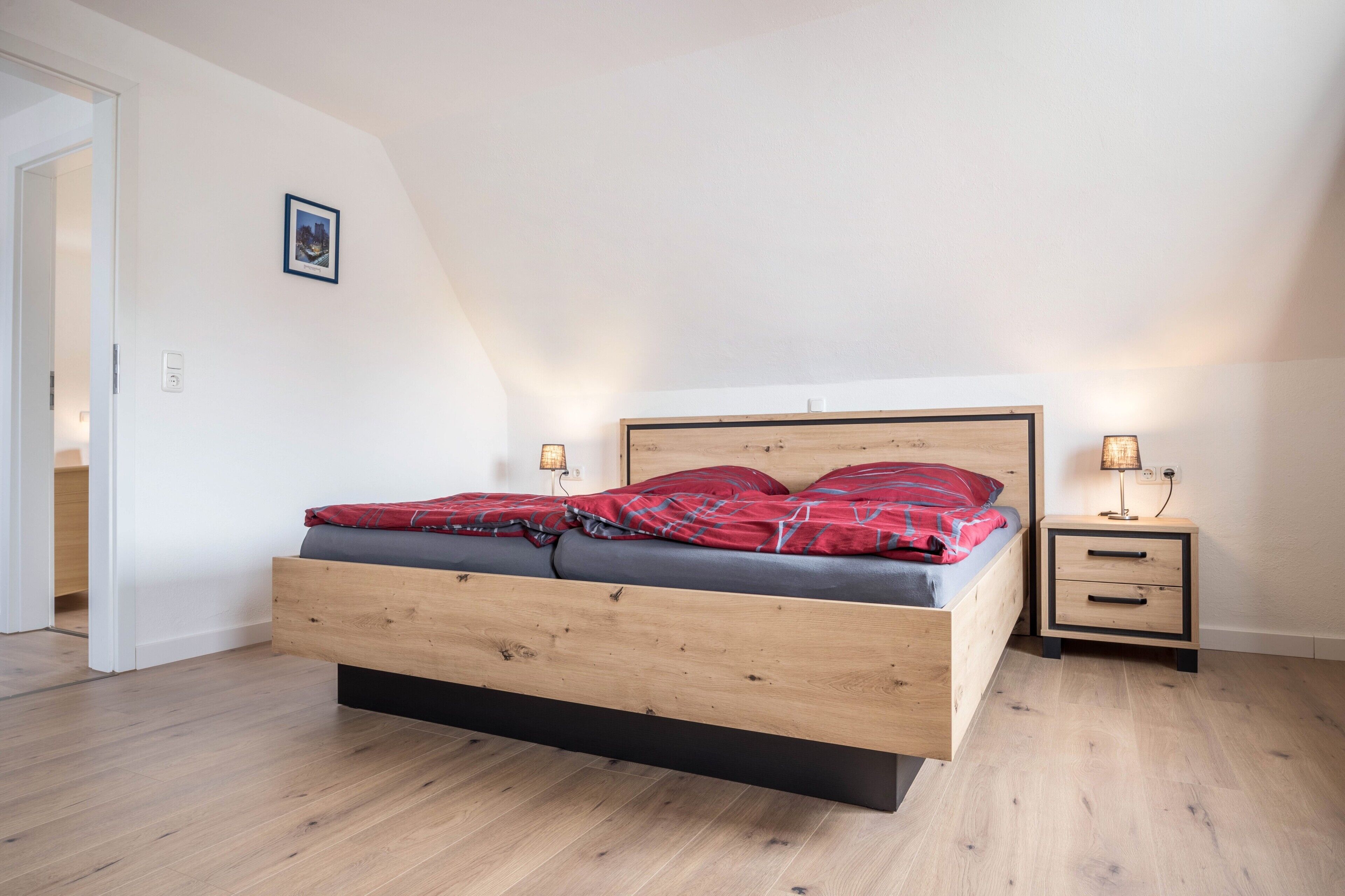 A bedroom with a wooden bed, bedside tables, and a door leading to another room.