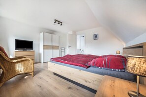 Une chambre à coucher comprenant un lit, une télévision, une armoire, une chaise et une table de chevet.