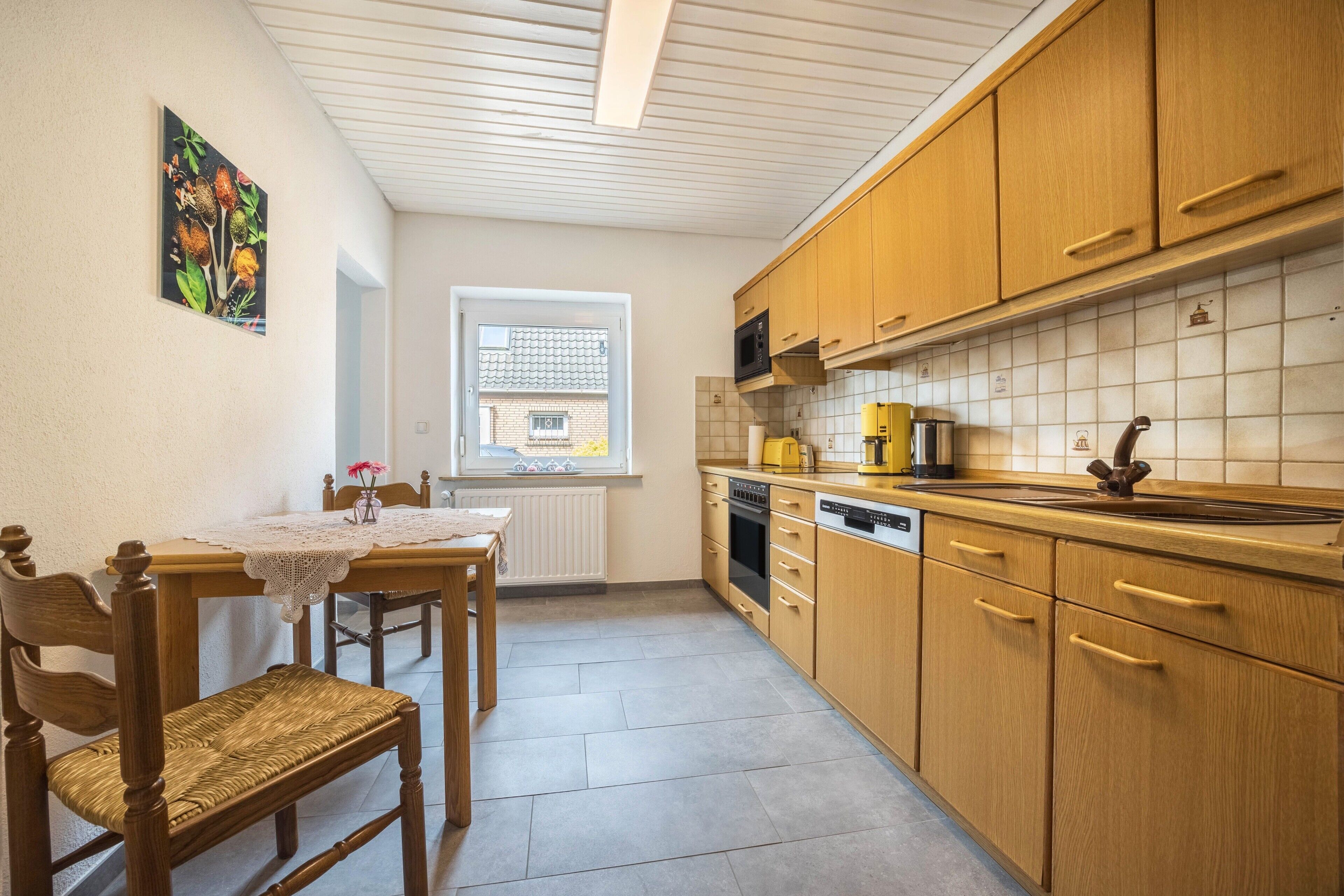 Una cucina con mobili in legno, un tavolo da pranzo con sedie, una finestra e un termosifone.