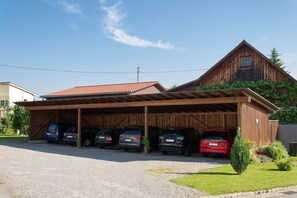A wooden building with a covered parking area and several cars parked in front.