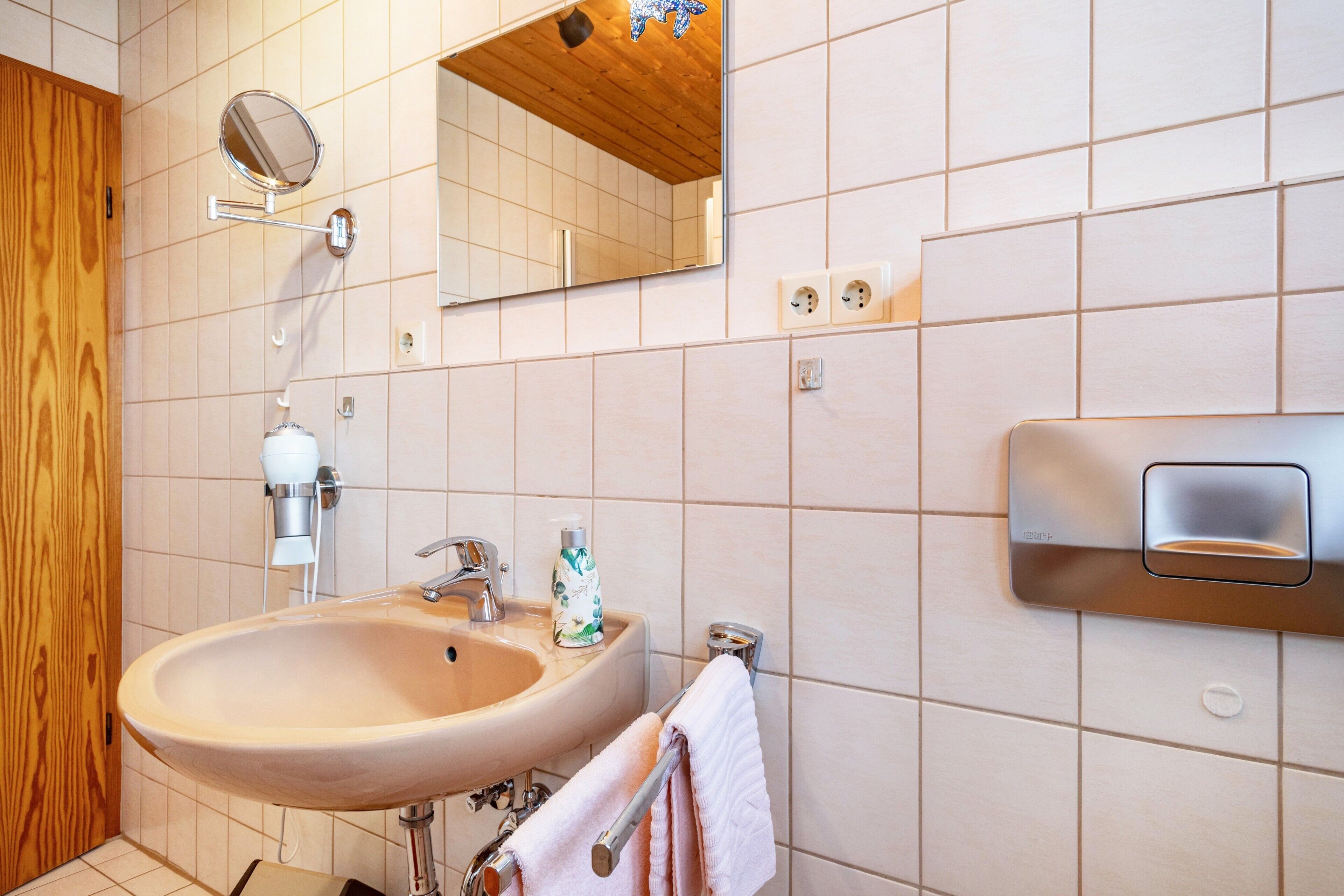A bathroom with a sink, mirror, towel rack, and wooden paneling.