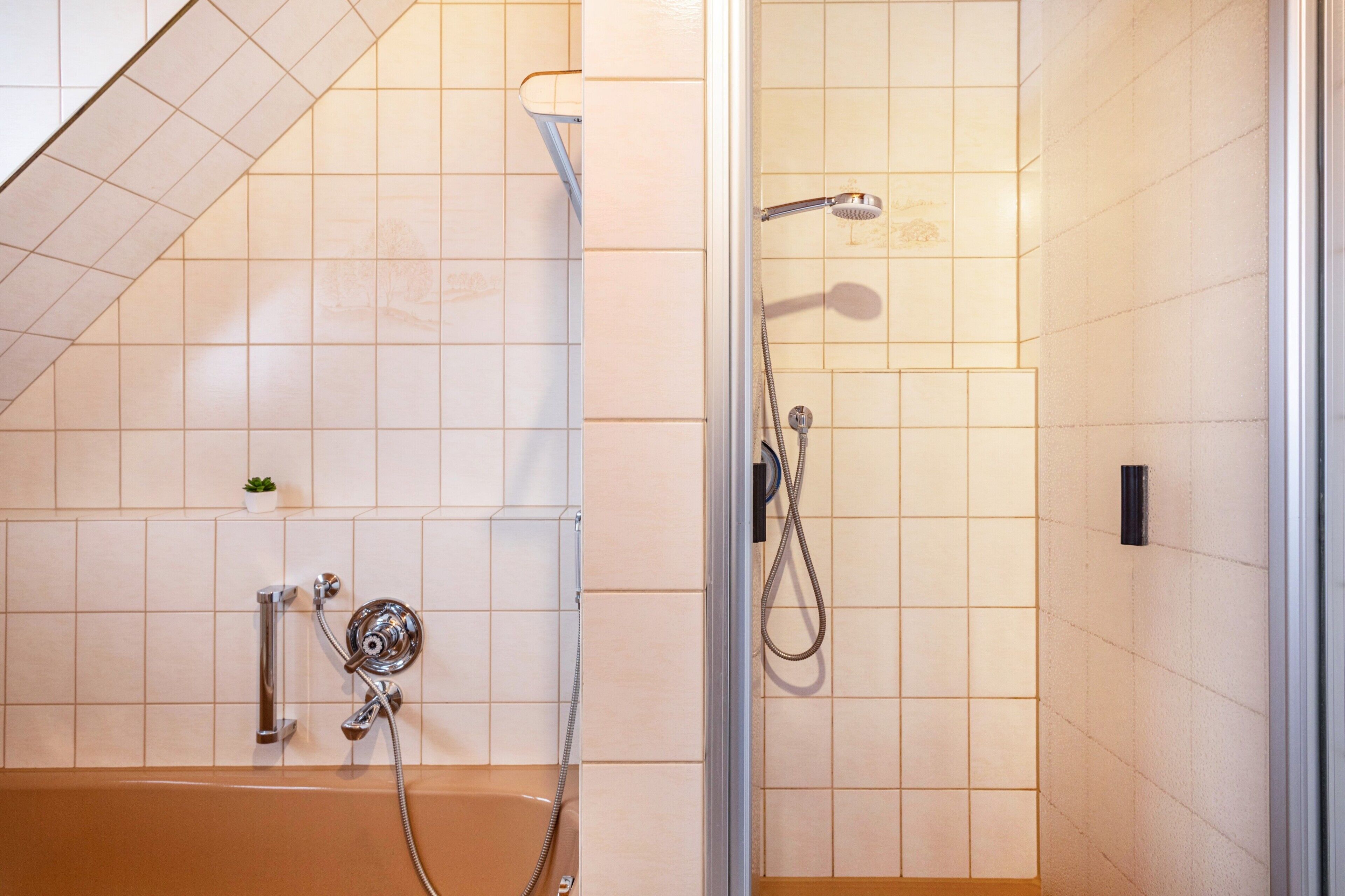 A bathroom with a bathtub, shower, and tiled walls.
