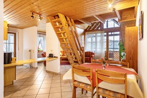A dining area with a wooden table, chairs, a staircase, and a view of the outside. - Apartment 'Ferienwohnung 6, 100qm' with Shared Garden, Balcony and Wi-Fi (Kressbronn am Bodensee)