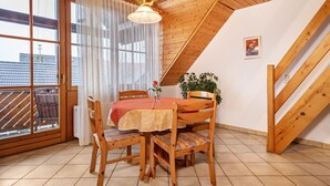 Ein Essbereich mit Tisch, Stühlen, einer Pendelleuchte und Blick durch ein Fenster.