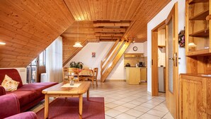 Ein geräumiger Wohnbereich mit Holzboden, einem Esstisch, einer Couch und einer Küche im Hintergrund.
