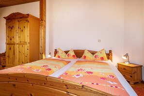 A bedroom with a wooden bed, a nightstand, a wooden wardrobe, and a wall-mounted light. - Apartment 'Ferienwohnung 5, 59qm' with Shared Garden, Balcony and Wi-Fi (Kressbronn am Bodensee)