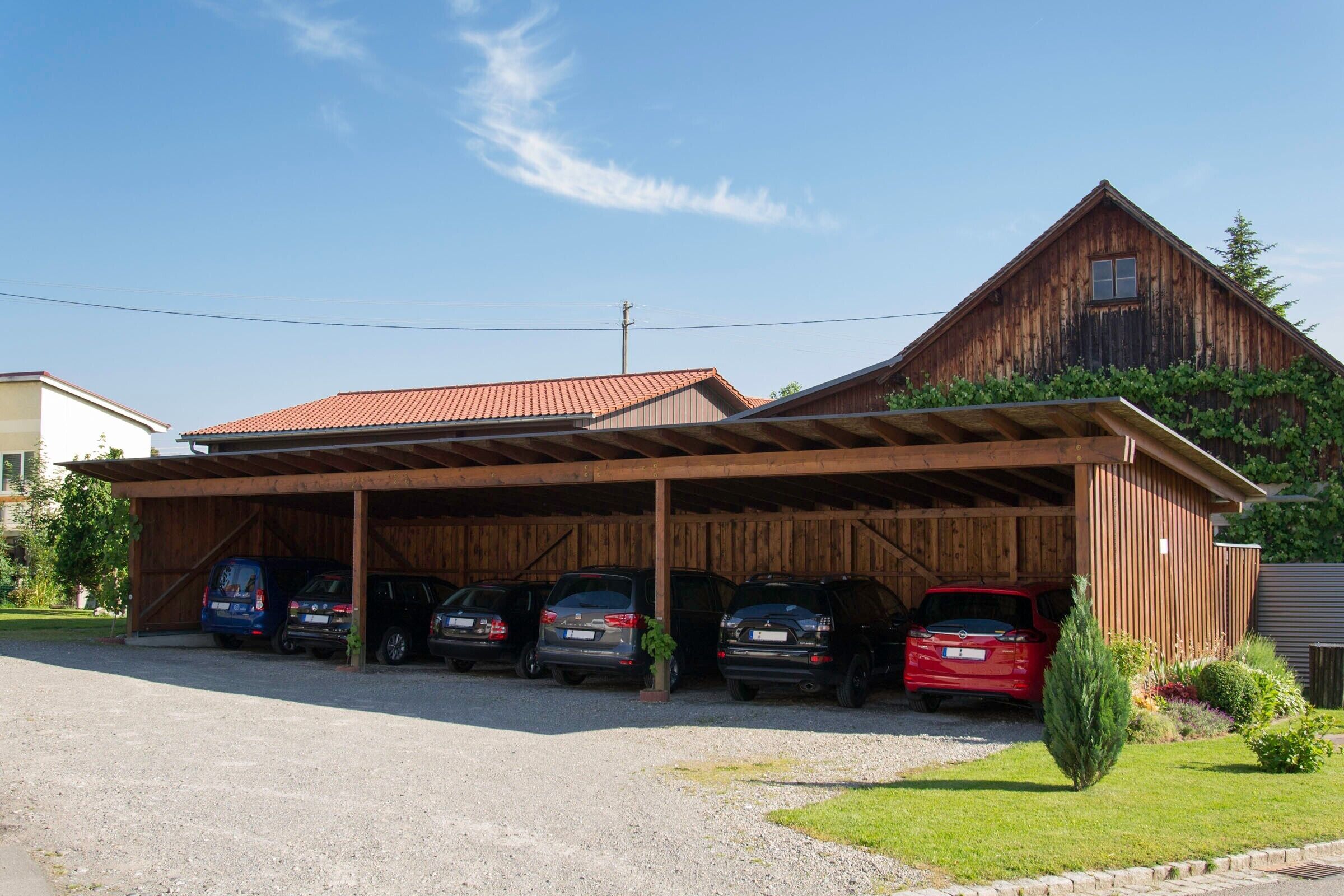 A wooden building with a covered parking area and several cars parked in front.