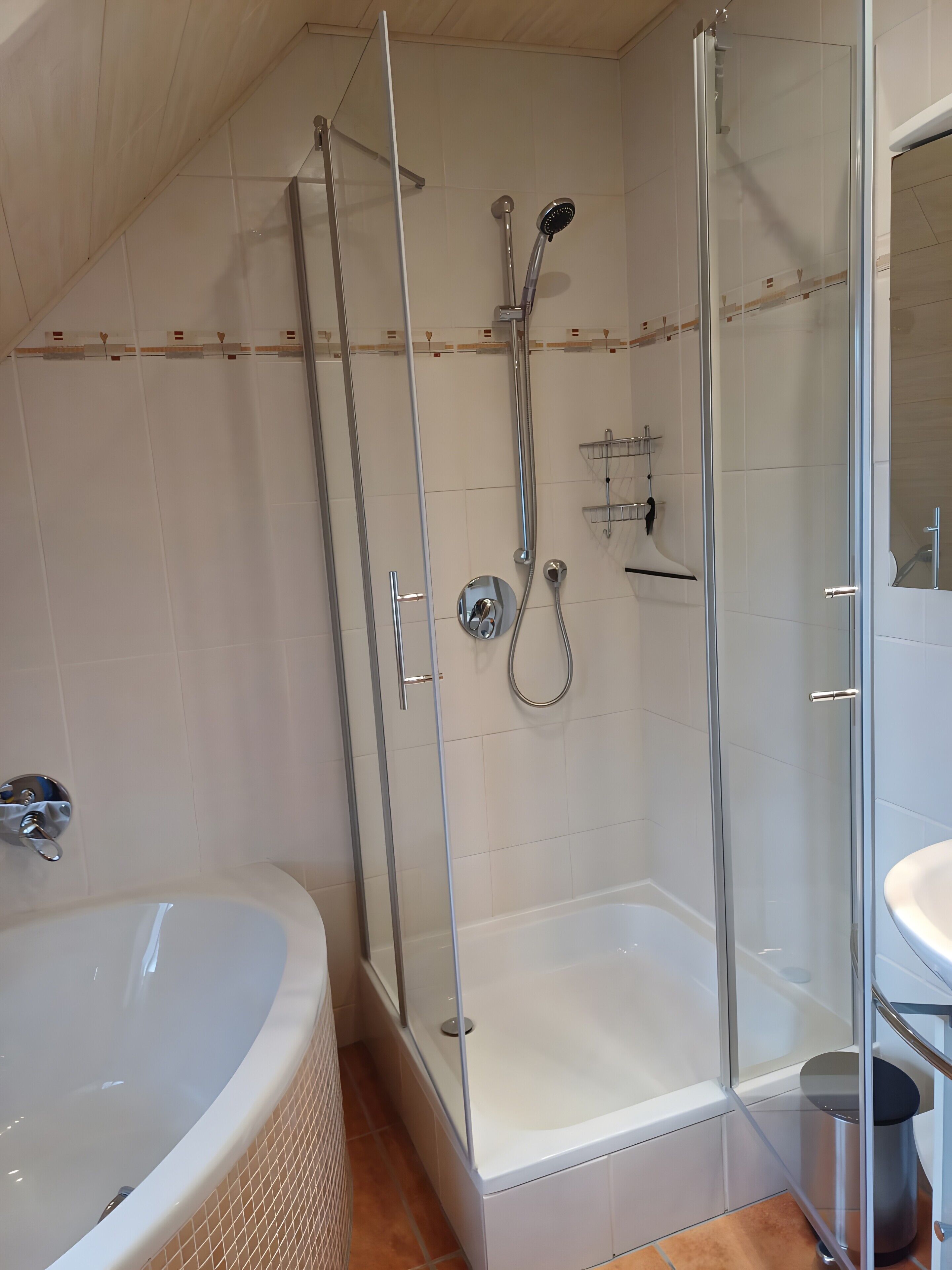 Un baño moderno con ducha envuelta en vidrio, bañera independiente y zona de lavamanos separada.