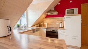 A kitchen with a wooden countertop, white cabinets, a microwave, a refrigerator, and a stove.