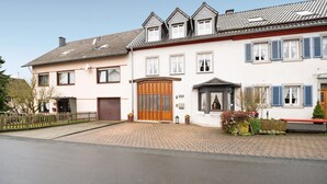 A two-story house with a large wooden door, a small porch, and a brick driveway. - Apartment 'Ferienwohnung Katharina' with Shared Terrace and Wi-Fi (Laufeld)