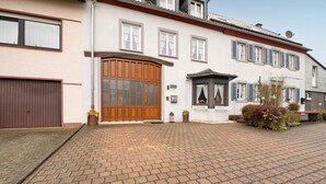 A two-story building with a large wooden front door, a satellite dish, and a paved driveway.