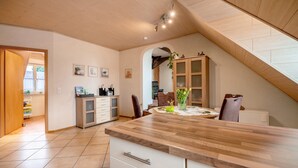 A kitchen with a wooden countertop, a dining area with a table and chairs, and a view of the outside.