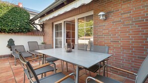 Un patio al aire libre con mesa y sillas, un muro de ladrillo y una antena parabólica.