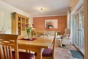 Un coin repas comprenant une table en bois, des chaises, un buffet et un tableau accroché au mur.