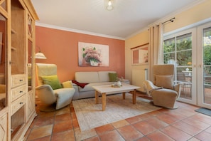 Un salon avec un canapé, un fauteuil, une table basse et un tableau accroché au mur.