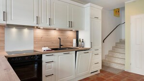 Una cocina con armarios blancos, horno negro y encimera de madera.
