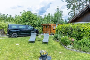 En skåpbil stod parkerad på en gräsyta, och i närheten fanns det två solstolar, en liten trähusvagn och en häck.