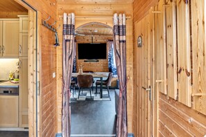 Un interior de madera con comedor, televisor y cocina.