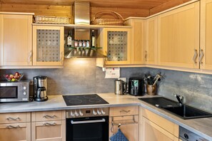 Eine moderne Küche mit Holzausstattung, einem Backofen, einer Kaffeemaschine und einem Wasserkocher.