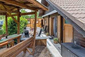 Eine Holzterrasse mit Tisch, Stühlen und einer Bank.